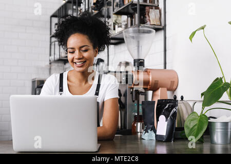 Young female cafe owner working on laptop Stock Photo