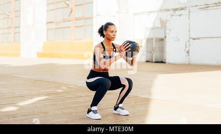Female athlete doing squat exercises with medicine ball Stock Photo