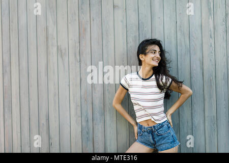 Young happy brunette posing at wall, outdoors shot Stock Photo