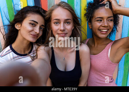 Group of young friends posing while taking selfie. Three smiling women having fun. Stock Photo