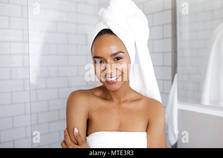 Portrait of an attractive young woman in her bathroom at home, wrapped a towel around head Stock Photo