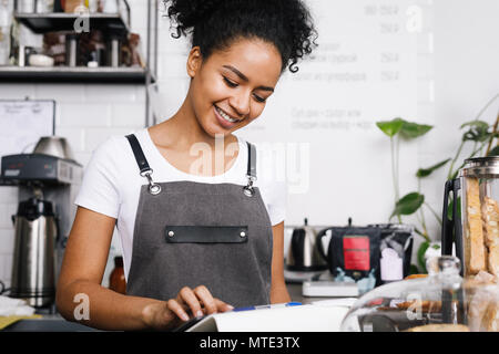 Smiling beautiful waitress using digital tablet in cafe Stock Photo