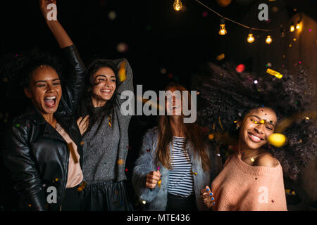 Young women at a party having fun with confetti Friends dancing outdoors. Stock Photo