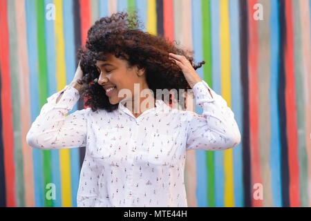 Young happy woman holding her hair, standing outdoors Stock Photo