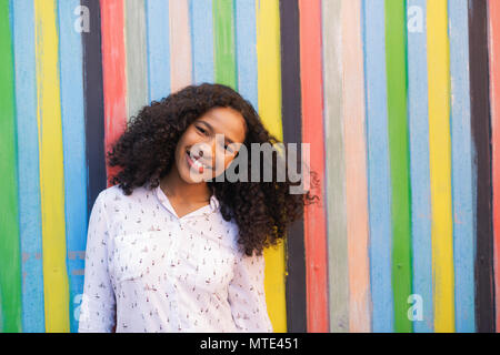 Beautiful smiling woman. Young brunette standing at the colorful wall. Stock Photo