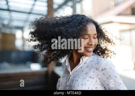 Young woman enjoying a day, posing outdoors with eyes closed Stock Photo