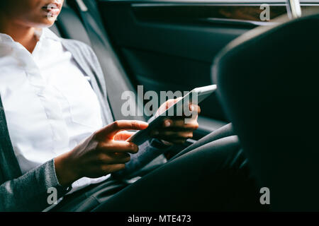 Unrecognizable woman using digital tablet, sitting on back seat of a car Stock Photo