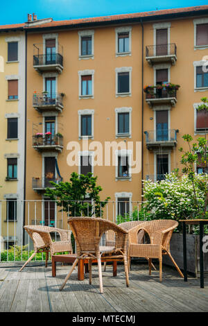 Wooden table and chairs on an outdoor terrace in a residential neighbourhood during the summer. Stock Photo