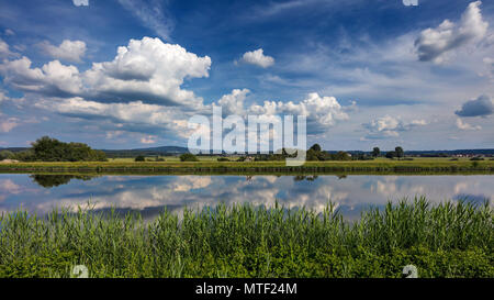 Dramatic clouds in blue sky reflect in the water of the the Rhine-Main-Danube Canal near Forchheim, Germany. Stock Photo
