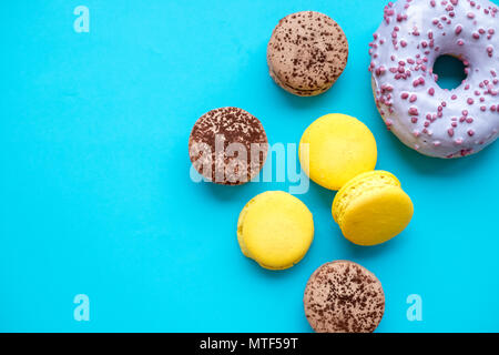 Different types of macaroons, donuts on blue candy background.Colorful and tasty French Macarons on blue background.Top view.Copy space