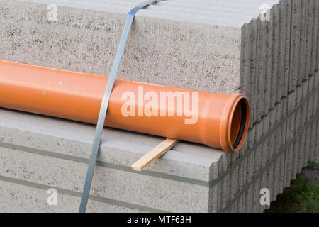 Concrete blocks and plastic pvc sewage pipe on palette on building