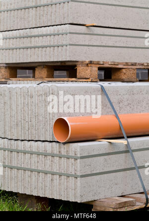 Concrete blocks and plastic pvc sewage pipe on palette on building