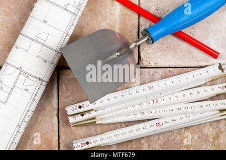 Trowel with folding rule, construction blueprint and pencil on bricks - home construction or renovation concept Stock Photo