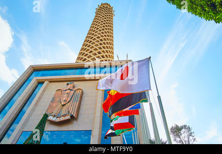 The view on Cairo Tower with National Emblem of Egypt above its entrance and flags of different countries on the foreground, Cairo, Egypt. Stock Photo