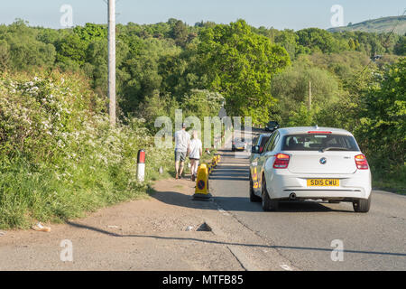 people walking towards entrance to Finnich Glen, Scotland, along side of A809 Stockiemuir Road past police cones to prevent dangerous parking Stock Photo