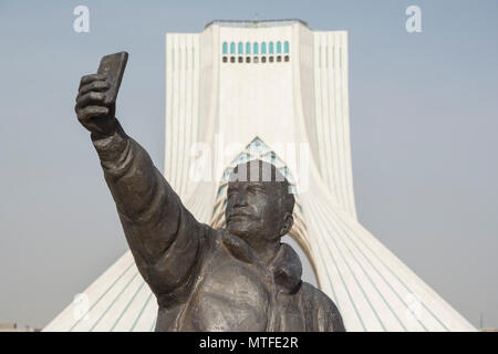 TEHRAN, IRAN - 7 May  2018 Taking a selfie with phone sculpture, Azadi tower at background  is a architecture landmark of Tehran Stock Photo
