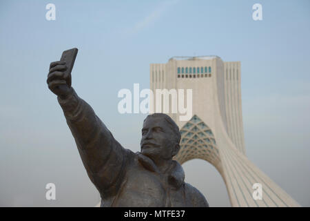 TEHRAN, IRAN - 7 May  2018 Taking a selfie with phone sculpture, Azadi tower at background  is a architectural landmark of Tehran Stock Photo