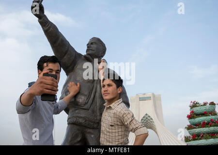 TEHRAN, IRAN - 7 May  2018 Young people taking selfie with selfie statue[sculpture] at Tehran Azadi square, Azadi Tower seen at background. Stock Photo