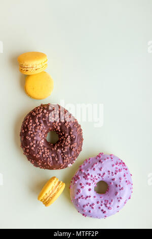 Glazed donuts and macaroons. Sweet dessert isolated on soft green background. Cakes with buttercream. lemon, yellow macaron cookies.Pop art color style.Selective focus. Copy space Stock Photo