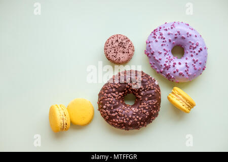 Pop Art Color style donuts, macarons and bakery goodies on bright colorful background.Minimalistic concept of donuts and french macaroons dessert.different pastel colors. glazed donuts with colorful sprinkles.Copy space Stock Photo