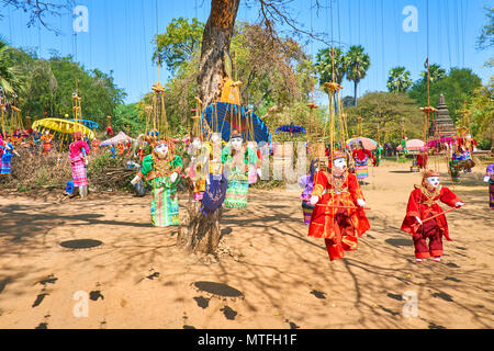 Traditional handmade string puppets in colored dresses and bright sunshades hang on the tree and flutter on the wind in archaeological site of old Bag Stock Photo