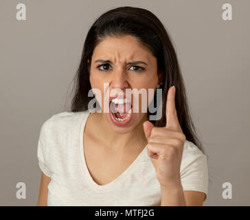 Close up portrait of an attractive young latin woman with an angry face. looking furious and crazy showing teeth and pointing finger at the camera. Hu Stock Photo