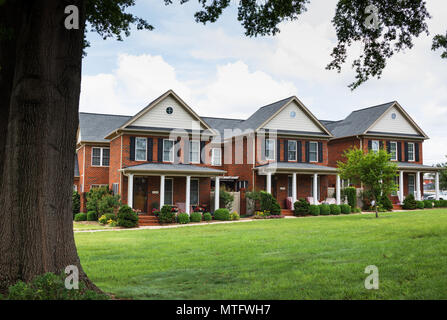 HICKORY, NC, USA-27 MAY 18:  A row of 3 elegant brick townhouses with an expanse of green lawn in front. Stock Photo