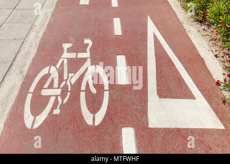 Bike lane. Bicycle sign and white directional arrow on red asphalt path Stock Photo