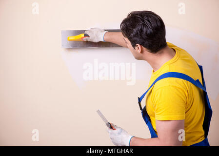 Young contractor employee applying plaster on wall Stock Photo