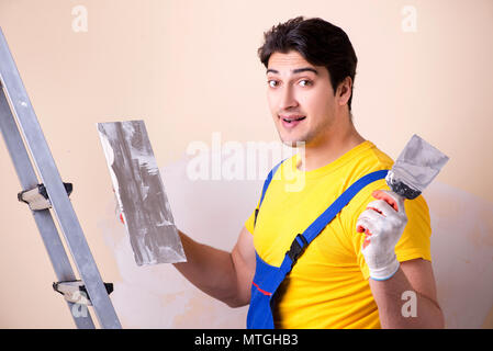 Young contractor employee applying plaster on wall Stock Photo