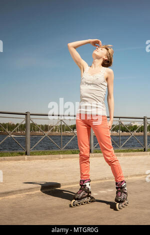 Happy young woman on roller skates at sunny day. Looking up, eyes closed. Warm toned image Stock Photo