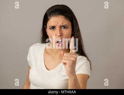 Close up portrait of an attractive young latin woman with an angry face. looking furious and crazy showing teeth and pointing finger at the camera. Hu Stock Photo