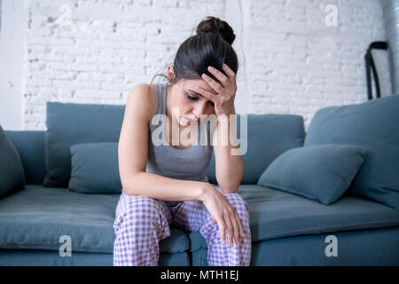 Beautiful latin depressed lonely woman staring out feeling sad, pain, grief at home on her sofa. Crisis, depression and mental health concept Stock Photo