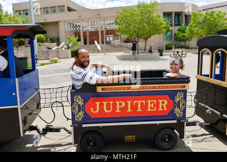 Father and daughter riding on a kids train Stock Photo