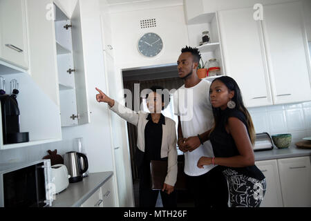 Estate agent showing couple the kitchen Stock Photo