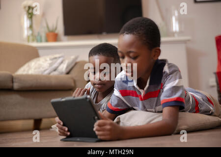 Boys looking at tablet on the floor Stock Photo