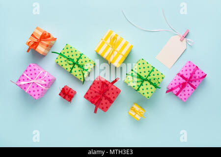 Holiday colorful gift boxes & blank gift tag tied with a ribbon on blue background. Birthday, Christmas sale concept. Stock Photo