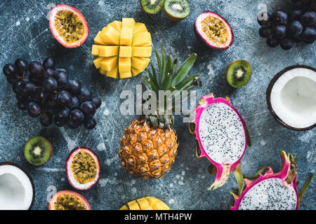 Tropical fruits, exotic fruits on concrete background. Fruit flat lay. Dragonfruit, passionfruit, coconut, mango, kiwi and grapes. Fresh raw fruit bac Stock Photo