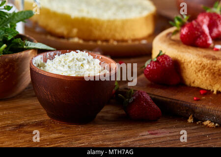 Butter in a bowl as main ingredient for baking strawberries cake on a wooden background, shallow depth of field, selective focus. Prepation for making Stock Photo