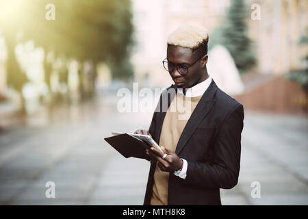 Businessman using his tablet computer in the city street Stock Photo