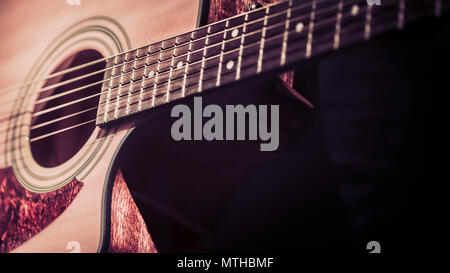 Man playing acoustic guitar on dark background, guitar closeup. A musical concept. Stock Photo