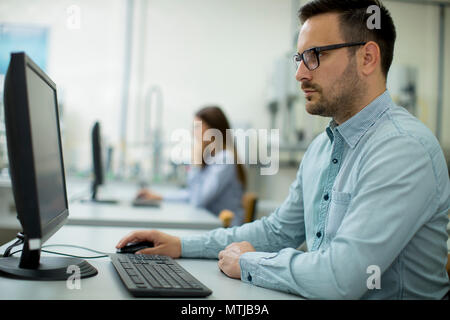 Side view of focused students using desktop pc in classroom at Technical faculty Stock Photo