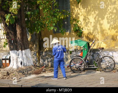 HOI AN, VIETNAM - 20TH MARCH 2018: Road sweeper worker with a broom cleaning the street in the center of world heritage city Hoi An Stock Photo