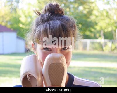 Beautiful Young Woman Smiling Behind Ballet Pointe Shoes Stock Photo