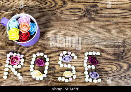 cup of button roses with the text rose formed with marshmallows on wooden table Stock Photo