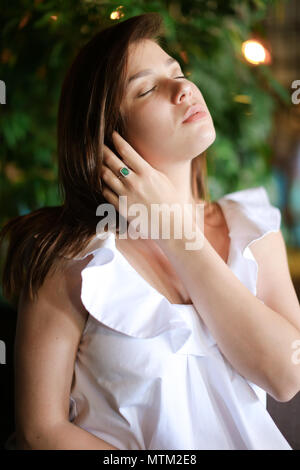 Portrait of relaxed woman in green background wearing white shirt. Stock Photo