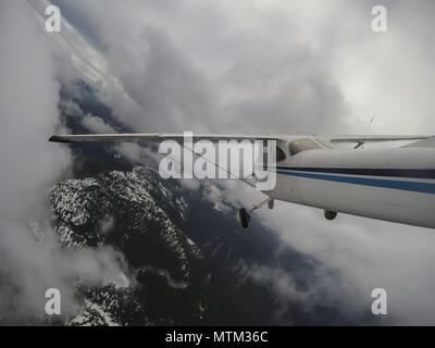 Airplane flying over the beautiful Canadian Mountain Landscape during a cloudy evening. Taken North of Vancouver, British Columbia, Canada. Stock Photo