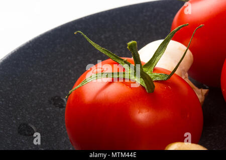 fresh ripe tomatoes and mushrooms - champignons on black ceramic plate on white background Stock Photo