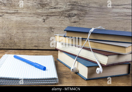 Blank notebook with pen, books earphone on wooden table Stock Photo