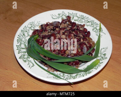 Bean salad decorated with green onion stalk on a plate with green ornament. Stock Photo